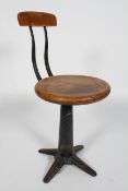 A Singer machinists stool, the revolving beech seat on a cast iron adjustable base,