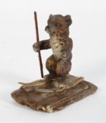A novelty lead cold painted figure of a skiing bear holding a skiing pole in one hand,