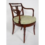 A Regency style mahogany elbow chair, the lyre back and scrolled arms above an oval caned seat,