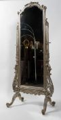 A silvered cheval mirror, the arched plate beneath a scrolling crest and on scrolling supports,