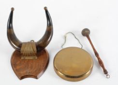 A brass dinner gong suspended from an oak shield,