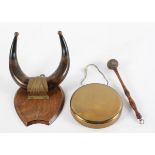 A brass dinner gong suspended from an oak shield,