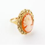 A yellow metal ring set with an oval carved cameo with abstract design mount.