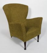 A 1950's style arm chair, the broad back above slightly flaring arms and stuffed over seat,