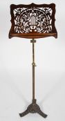 A Victorian fret work music stand, on a telescopic brass and iron base,