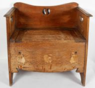 An Arts and Crafts oak settle or chair, with a pierced motif to the back and handles to the sides,