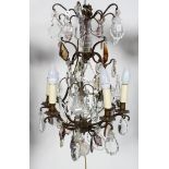 A bronzed metal and cut glass chandelier, with six lights on a scrolling frame,