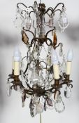A bronzed metal and cut glass chandelier, with six lights on a scrolling frame,