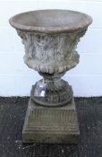 A reconstituted stone garden urn with foliate swag decoration on a socle base and square section