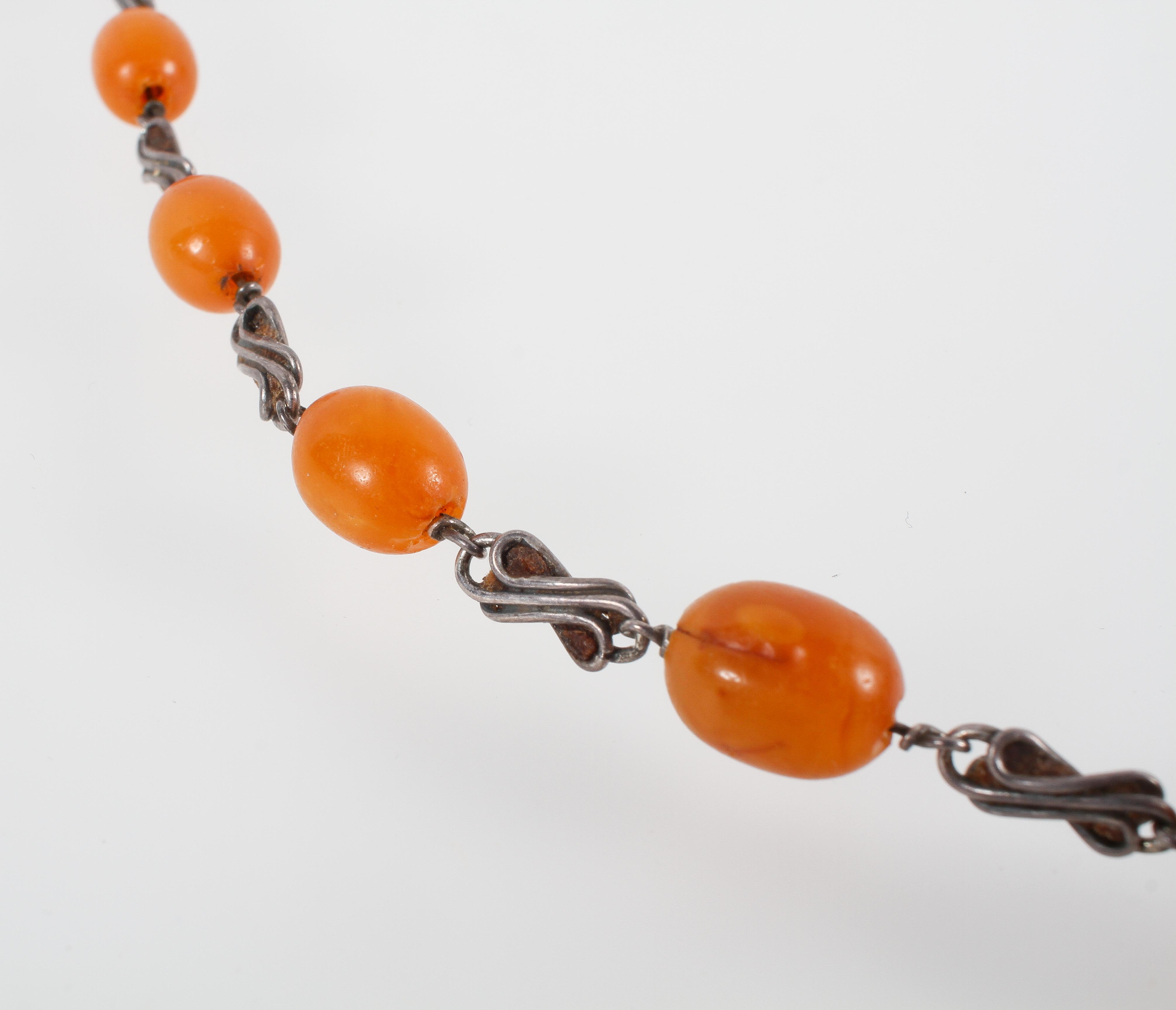 A long necklace having abstract design links inter spaced with graduated orange beads. - Image 2 of 2