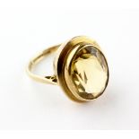 A yellow metal single stone ring set with an oval faceted cut citrine quartz