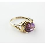 A yellow metal ring principally set with a triangle cut amethyst