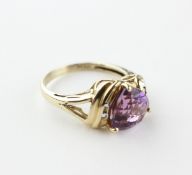 A yellow metal ring principally set with a triangle cut amethyst