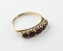 A yellow metal half hoop ring set with five graduated garnets.