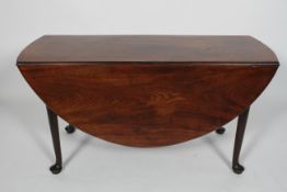A Georgian mahogany oval drop leaf dining table, with tapering legs on pad feet,