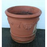 A large terracotta planter, or tapering cylindrical form, with swags and masks in relief,