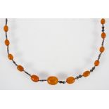 A long necklace having abstract design links inter spaced with graduated orange beads.