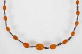 A long necklace having abstract design links inter spaced with graduated orange beads.