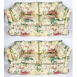 A pair of modern sofas with floral upholstery on loose cushions, a geometric fabric beneath,