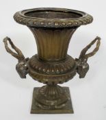 A bronze campana urn, with a fluted body and pair of rams head handles,