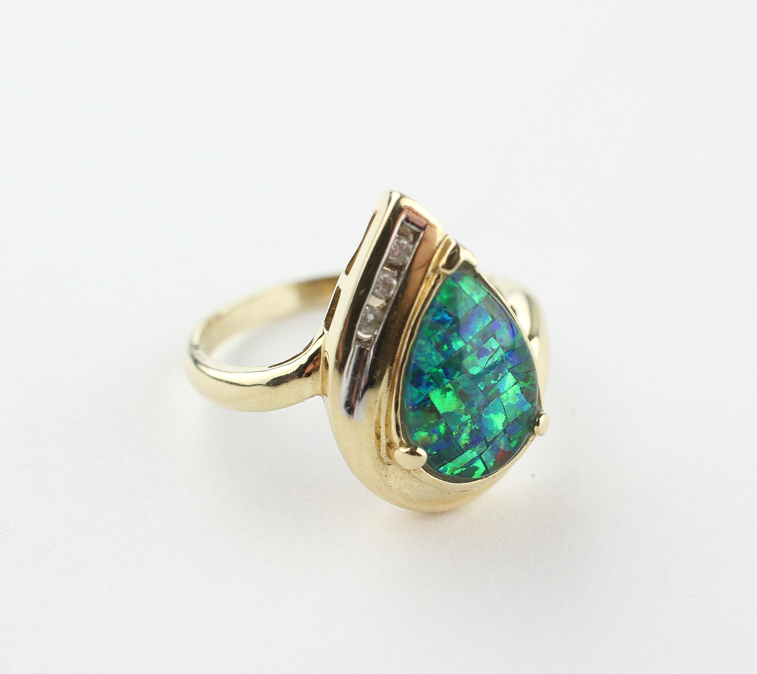 A yellow metal ring set with a synthetic mosaic opal triplet and finished with three diamonds.