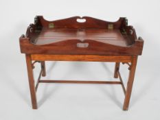 A Georgian style mahogany butlers' tray and stand, the tray with pierced handles and drop sides,