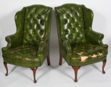 A pair of George II style wing back arm chairs, with green leather buttoned upholstery,