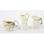 Three Belleek Parian jugs, comprising : a shell shaped example,