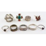A collection of eight rings of variable designs, size ranges from J to R and a scarf ring.