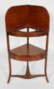 A George III mahogany corner washstand, with raised back, single drawer and shaped stretcher,