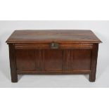 An 18th century oak coffer, the two plank top above a carved top rail and triple panel front,