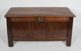 An 18th century oak coffer, the two plank top above a carved top rail and triple panel front,