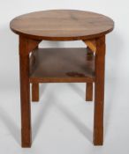 An Arts and Crafts oak circular occasional table, with chamfered legs and a shelf,