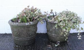 A pair of reconstituted stone planters, or circular form, with flower head decoration,