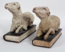 A pair of 15th century style carved wood sheep, recumbent on books,