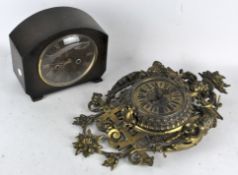 An ornate brass wall clock, the dial with Roman numerals denoting hours,
