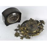 An ornate brass wall clock, the dial with Roman numerals denoting hours,