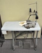 An industrial sewing table with Pegasus machine and anglepoise style lamp attached, with tedle base,