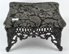 A vintage cast metal footstool, with upholstered top,