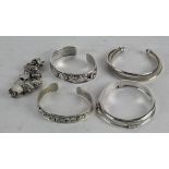 Four silver bangles, one white metal and a silver bracelet,