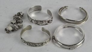 Four silver bangles, one white metal and a silver bracelet,