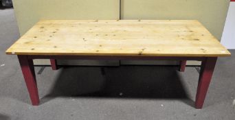 A large rectangular pine kitchen table island, with red painted square tapering legs,
