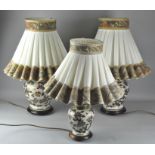 A pair of Japanese style table lamps, ceramic, and a smaller example, all with shades,