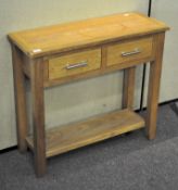 A contemporary oak side table, with frieze drawers and lower tier shelf, all raised on square legs,