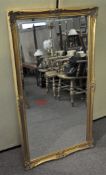 A large gilt framed wall mirror of rectangular form with bevelled edge,