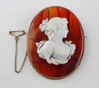 A large banded agate brooch with carved cameo. In a yellow metal rope edge mount.