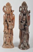 Two Chinese root carvings of Buddhist figures, each carrying a ball and with other attributes,