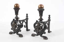 A pair of Victorian bronze and iron fire dogs, with orb finial and scrolling legs,