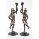 A pair of Spelter figure candlesticks, cast as warriors holding up torches, with gilt highlights,