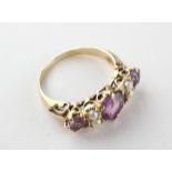 A yellow metal half hoop ring set with amethyst and seed pearls. No hallmark - stamped 9ct.